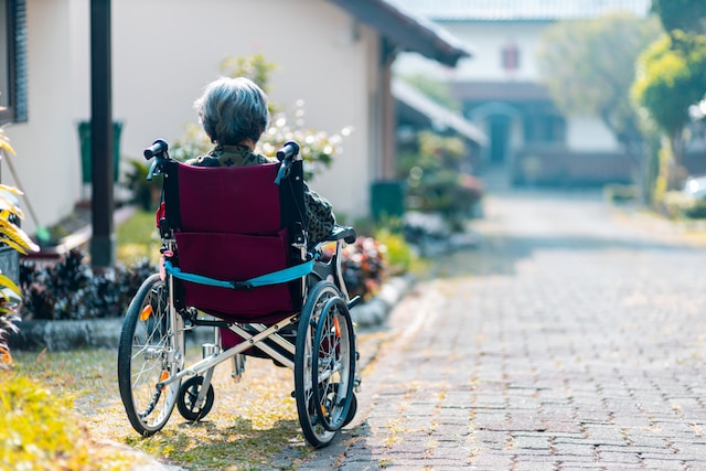 An old lady on wheel chair on brick floor street